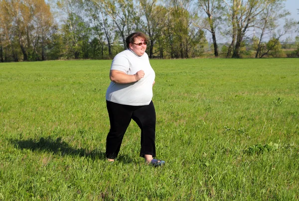 Übergewichtige Frau läuft auf Wiese — Stockfoto
