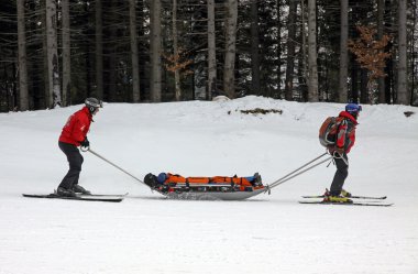 Ski rescuers are transporting injured skier clipart