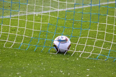 Soccer ball inside the net on the green grass field clipart