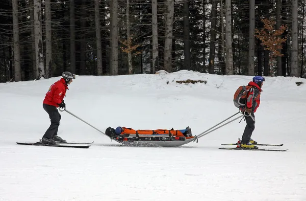 Ski räddningsarbetare transporterar skadade skidåkare — Stockfoto
