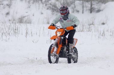 The moto bike's driver rides over snow track clipart