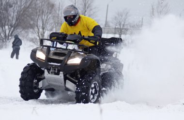 The quad bike driver rides over snow track clipart