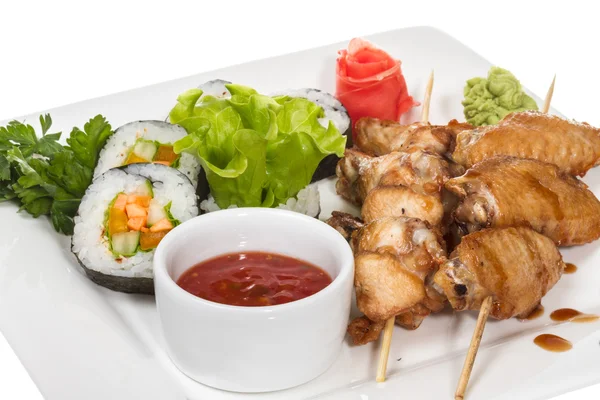Buffalo chicken wings on plate with sushi — Stock Photo, Image