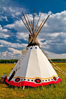 An indian teepee set up in a meadow among pine woods (portrait o clipart