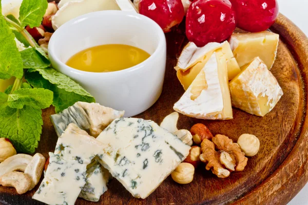 Různé druhy sýrů s medem, ořechy a hrozny na desku, je — Stock fotografie