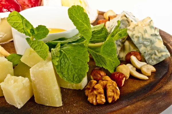 Vários tipos de queijo com mel, nozes e uvas no prato, é — Fotografia de Stock