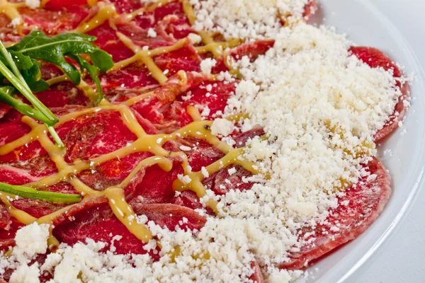 stock image Meat (beef) Carpaccio with Parmesan Cheese and ruccola