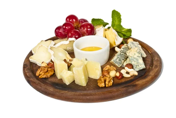 Various types of cheese with honey, nuts and grapes on plate, is — Stock Photo, Image