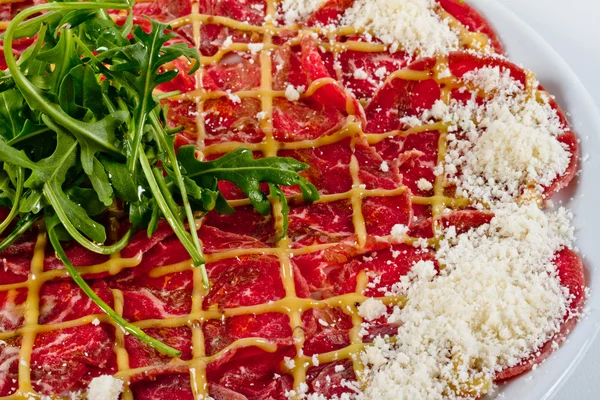 stock image Meat (beef) Carpaccio with Parmesan Cheese and ruccola