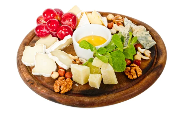 Varios tipos de queso con miel, frutos secos y uvas en el plato, es —  Fotos de Stock