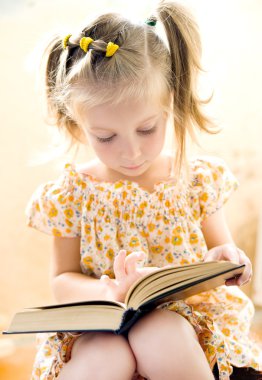 Küçük kız kitap okuyor.