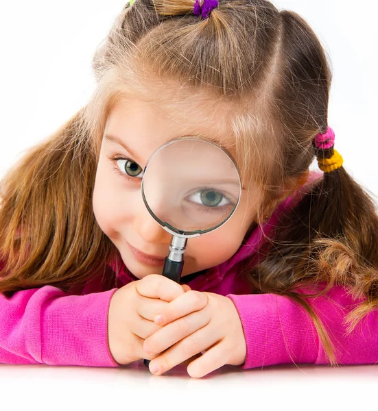 Girl looking through a magnifying glass — Stock Photo, Image