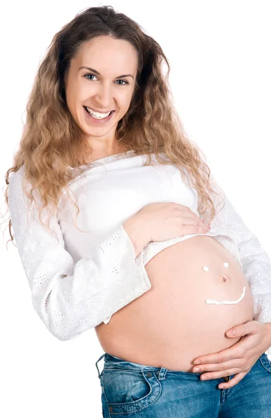 Беременная молодая женщина с косметическим кремом на животе — стоковое фото
