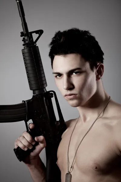 Schöner Soldat mit nacktem Oberkörper hält ein Gewehr — Stockfoto
