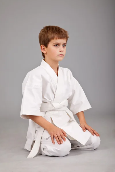 Хлопчик карате в білому кімоно сидить — стокове фото