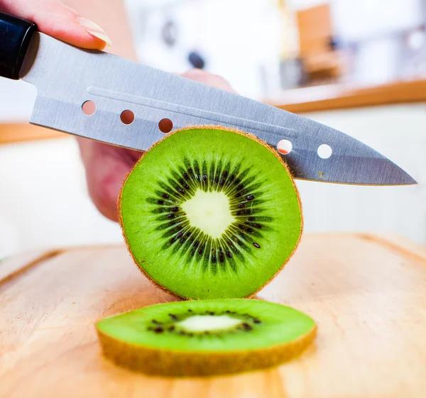 Vrouw handen snijden kiwi — Stockfoto
