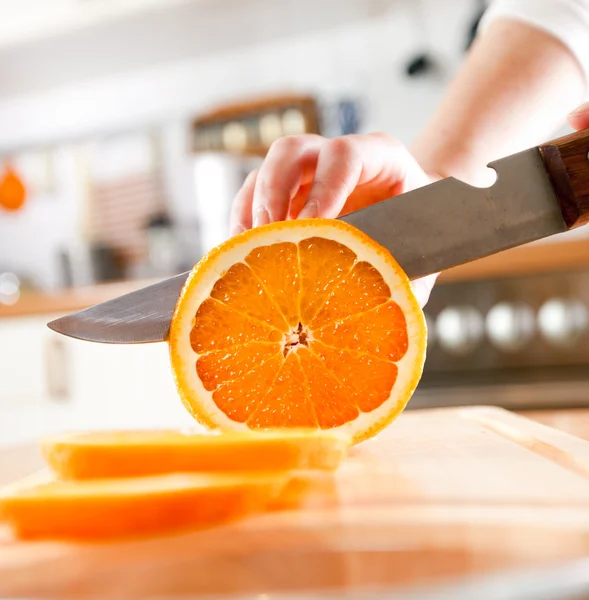 Vrouwenhanden die oranje snijden — Stockfoto