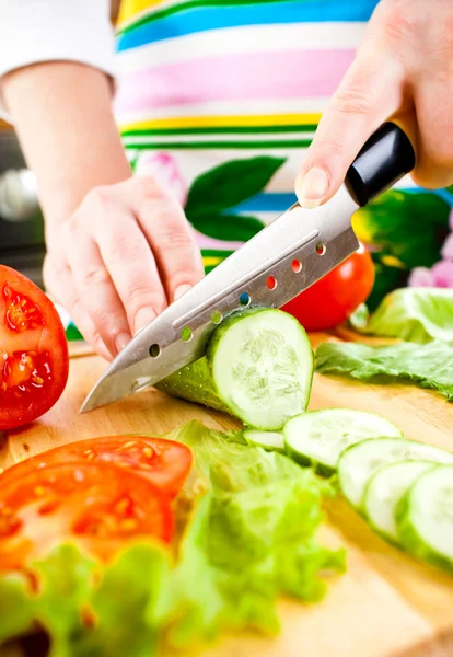 Mains de femme coupant des légumes — Photo