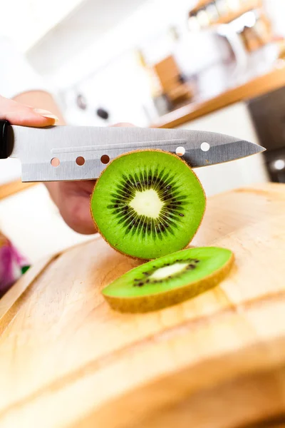 Mãos de mulher cortando kiwi — Fotografia de Stock