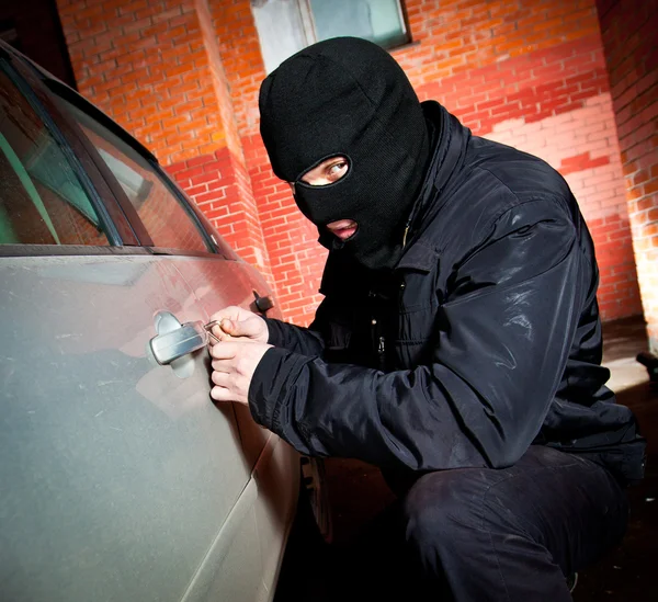 O ladrão e o ladrão com uma máscara sequestram o carro — Fotografia de Stock