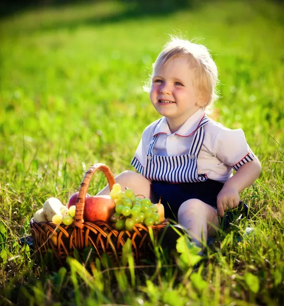 Kleiner Junge mit einem Korb voller Früchte — Stockfoto