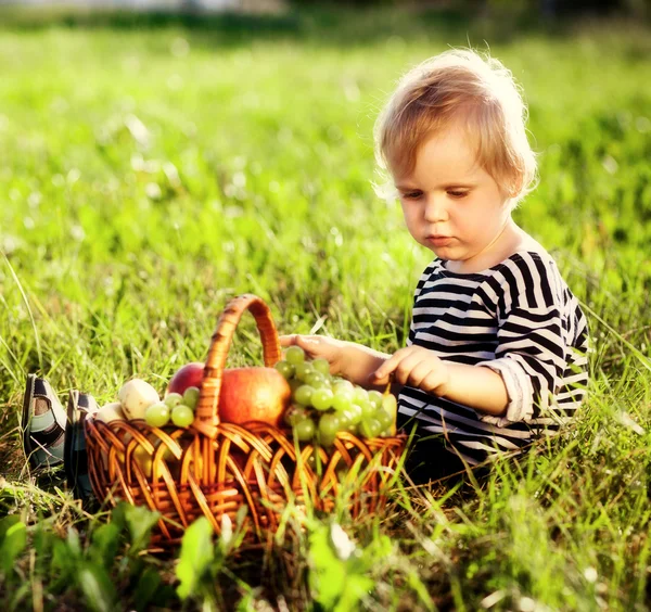 Kleiner Junge mit einem Korb voller Früchte — Stockfoto
