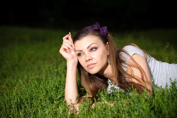 Porträtt av en vacker ung kvinna liggande på gräset — Stockfoto
