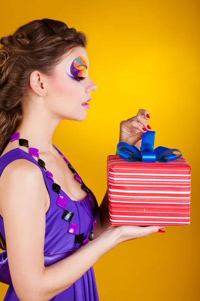 Young beautiful woman with make up is opening gift — Stock Photo, Image