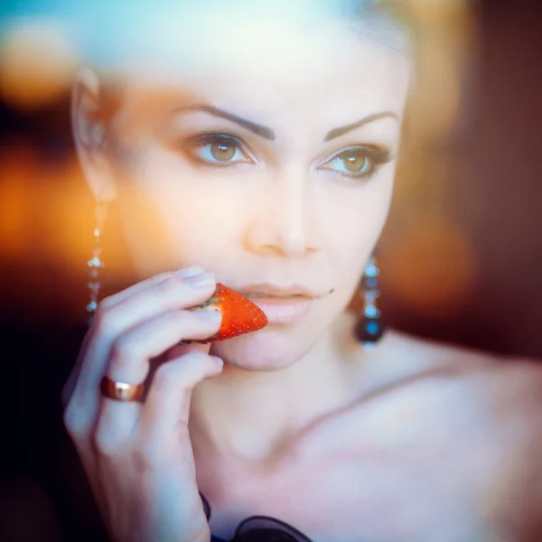 Retrato de uma mulher bonita com morango na mão — Fotografia de Stock