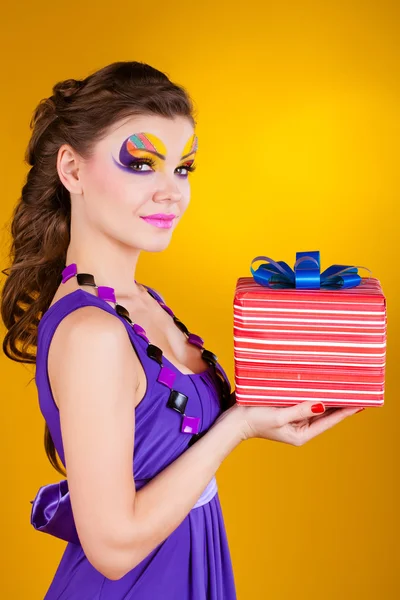 Schöne Frau mit Make-up im Kleid mit einem Geschenk — Stockfoto