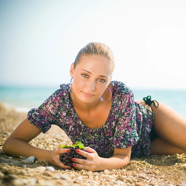 Donna sorridente con uva in spiaggia — Foto Stock