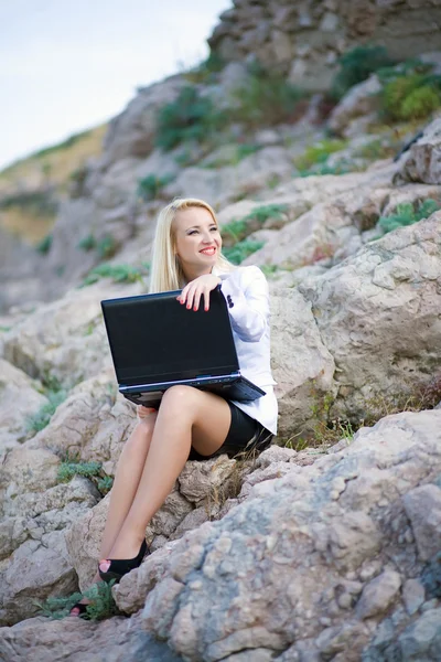 Hermosa mujer en la orilla del mar con un ordenador portátil — Foto de Stock