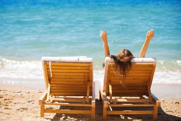 Vrouw op een tropisch strand op een chaise lounge — Stockfoto