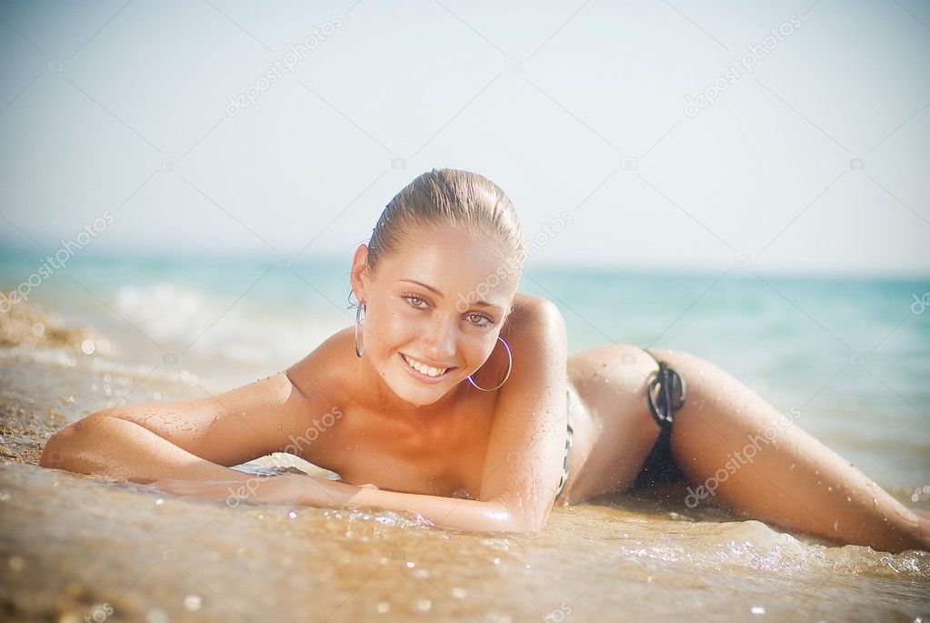 Beautiful young woman on the sand on the seashore
