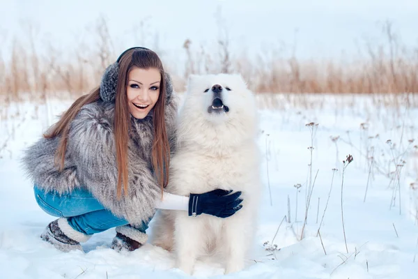 Gelukkige vrouw met Samojeed hond in winter forest — Stockfoto