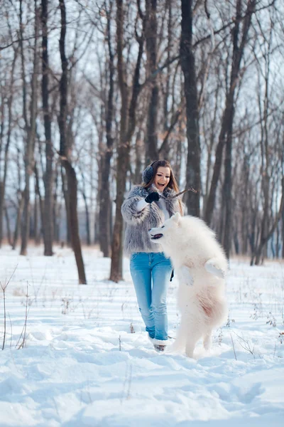 Donna felice con cane Samoyed nella foresta invernale — Foto Stock