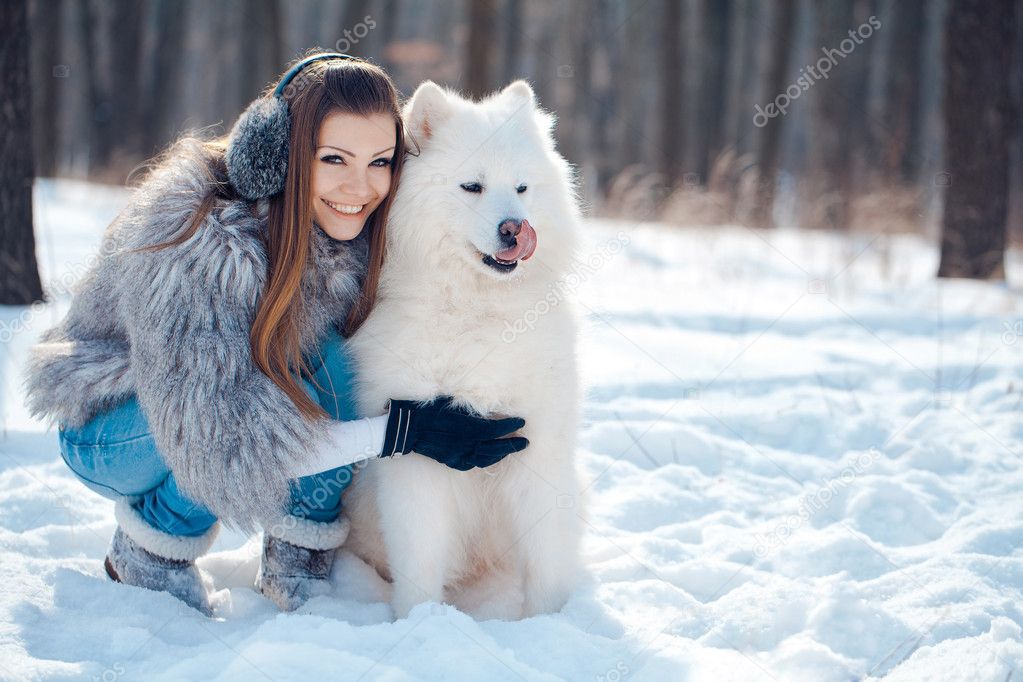 Happy woman with Samoyed dog in winter forest