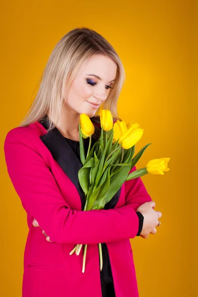 Cute teen bruneta dívka s tulipány na žlutém podkladu — Stock fotografie
