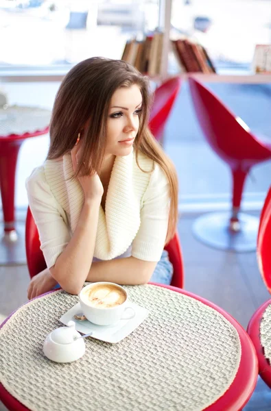 Mujer joven y bonita sentada en el café con una taza de té — Foto de Stock