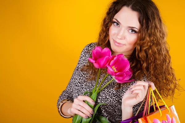 Vacker kvinna med blommor och väskor på gula — Stockfoto