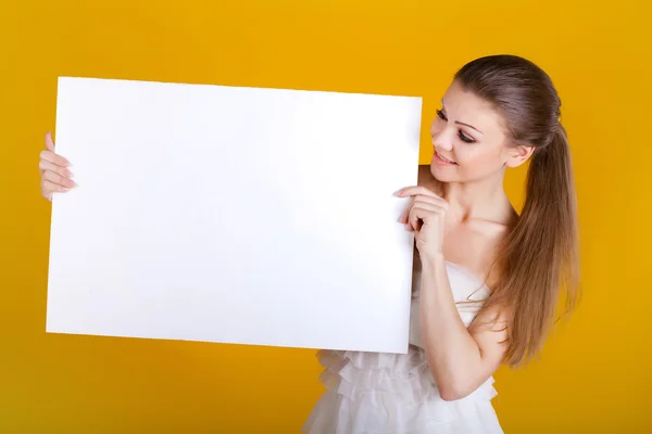 Улыбающаяся женщина с белым пустой на желтом фоне — стоковое фото