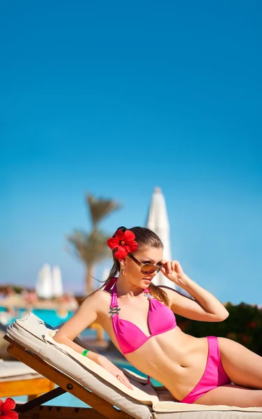Schöne Frau an einem tropischen Strand auf einer Chaiselongue — Stockfoto