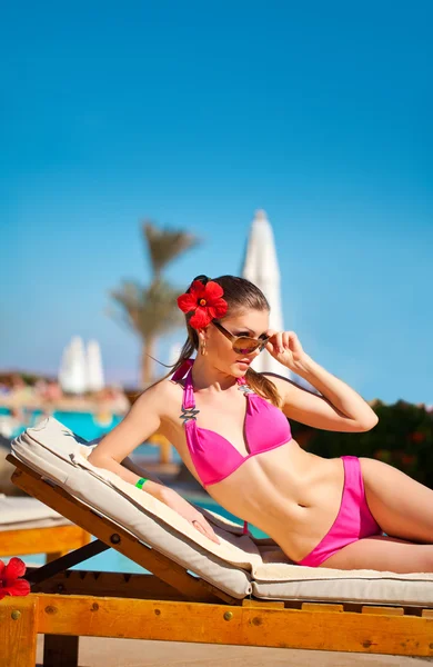 Beautiful woman on a tropical beach on a chaise lounge — Stock Photo, Image