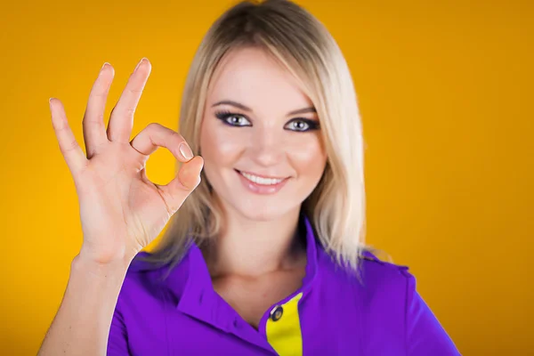 Happy smiling beautiful young woman showing okay on yellow — Stock Photo, Image