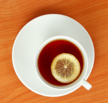 Tea cup with lemon on wooden table from above clipart