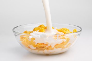 Milk stream flowing to the bowl with corn flakes clipart