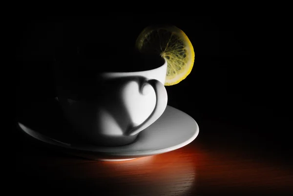 Xícara com limão no escuro — Fotografia de Stock