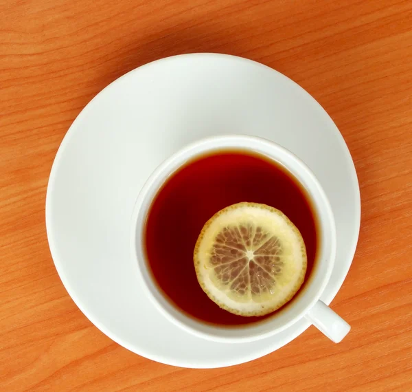 Ένα φλυτζάνι τσάι με λεμόνι στο ξύλινο τραπέζι από ψηλά — Φωτογραφία Αρχείου