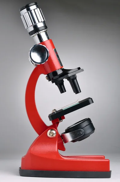 Червоний мікроскоп на сірому фоні — стокове фото
