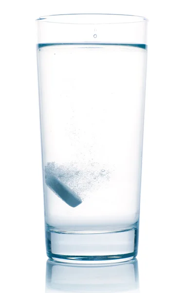 Tablet ve sklenici vody, izolované na bílém — Stock fotografie